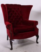 A 20th century antique style wingback armchair raised on cabriole legs with pad feet having red