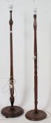 A near pair of early 20th century standard lamps in oak , both with turned stems on terraced bases.
