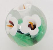 A Langham glass paperweight with white lillies and green leaf control bubble base.