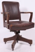 A 1930's oak Industrial office swivel chair raised on quadruped base with burgandy vinyl seat and