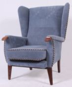 A good shaped 1950's Parker Knoll style wingback armchair raised on turned legs with blue
