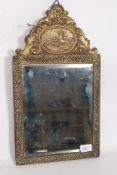 A vintage brass mirror, having  a farm and mill scene in repousse above a bevelled edge mirror.