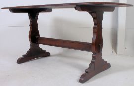 An Ercol 1970's Windsor pattern beech and elm wood refectory dining table being raised on shaped