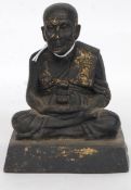 An eastern bronze figurine of a meditating monk bearing original traces of gilding raised on plinth