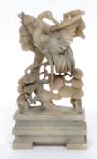 A Chinese soapstone figurine of a stork in a peony tree set on a raised socle soapstone plinth.