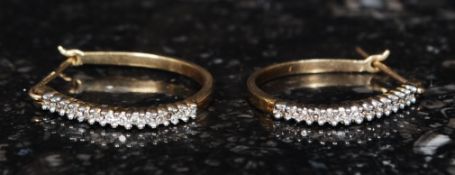 A pair of ladies 9ct gold and diamond earrings being channel set.