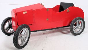 A hand built go-kart of wooden construction having red painted finish set on good pram wheels