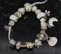 A beautiful white metal charm bracelet having moon charm, handbag charm, penguin and many others,