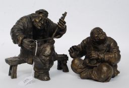 A pair of heavy cast vagabond bronze figurines, one of a musician and one of a shoesmith.
