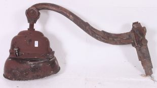 A large vintage industrial work light on large cast iron shaped bracket with unusual shaped light.
