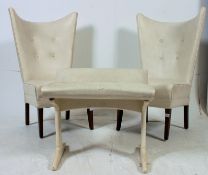 A stunning pair of retro 1950's batwing nursing chairs having white vinyl seats being raised on