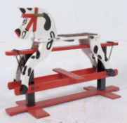 A 1950's wooden retro rocking horse of pied colour raised over a red glider.