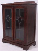 A good quality 1920's oak leaded glass display cabinet having twin doors with shelved interior set