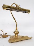 A 20th century vintage style brass desk lamp having a pen tray attached to the base