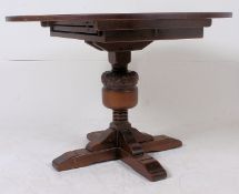 An extendible circular oak pedestal dining table having a concealed fold out leaf above the