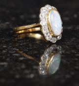 An 18ct gold, diamond and opal ring, the oval cabochon cut stone with diamond surround,