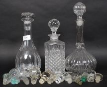 Three vintage glass decanters along with a selection of decanter and bottle stoppers
