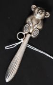 A Victorian style silver metal babies rattle, having a teddy bear abode a banded stem.