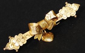 A 9ct gold bar brooch with bow and floral motif with heart pendant. Marked H&W 9ct. Total weight 1.