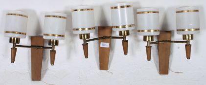A set of three mid century retro teak and glass wall lights, retaining the original pull cords.