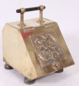 An Arts & Crafts brass coal purdonium with ebony carrying handle and embossed design to front.