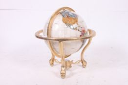 A contemporary lapis and gemstone inlaid world globe in rotating cradle with polished brass frame.