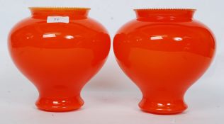 A pair of retro orange glass light / lamp shades, having a bulbous body.