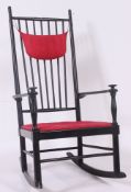 A Scandinavian ebonised rocking chair having spindle back, seat pad and makers sticker for Gemla.