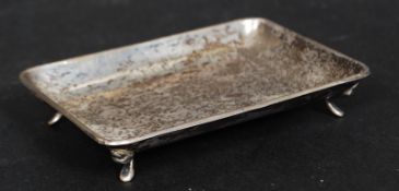 A hallmarked silver pin tray standing on four raised silver feet.