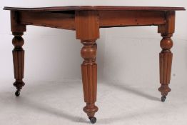 A Victorian mahogany dining table raised on reeded tapering legs with flared top above.