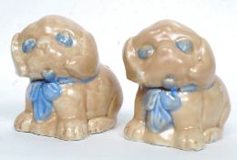 A pair of 1930's Sylvac style ceramic ornaments of puppy dogs, each with blue bows.