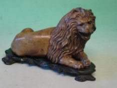 A Hardstone Lion Finely carved in recumbent pose. Raised on a hardwood stand. 6 ¼