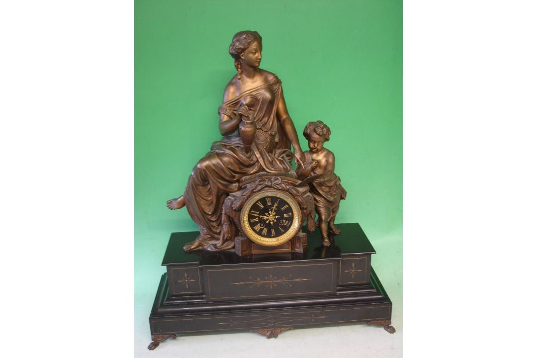 A French Mantle Clock Black slate and speltar. Surmounted by a classical lady teaching a child to