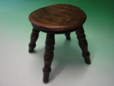 A Welsh Milking Stool. The moulded round top raised on splayed turned legs. 7 ¾