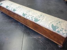 A Victorian Walnut Footstool of sarcophagus form with upholstered top raised on bun feet. 41 ½