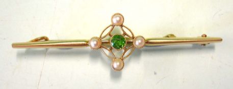 A Gold Bar Brooch. Set with a green stone and four split pearls. Marked 15ct. Condition report: