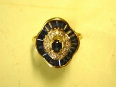 A Sapphire and Diamond Ring The centre stone with a ring of diamonds and pave set baguette sapphires