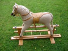 A Rocking Horse The fabric body with leather saddle and stirrups, raised on a trestle support. 35