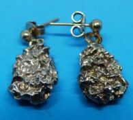 A pair of earrings fashioned as gold nug