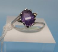 A white metal ring set with a central am