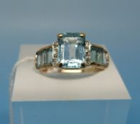 A yellow metal ring set with seven aquam