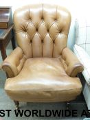 A leather button back armchair raised on