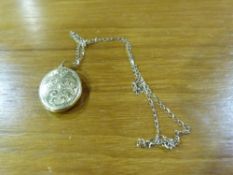 A yellow metal locket on chain, stamped