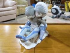 A Lladro figure of two children on a sle
