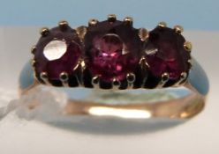 A yellow metal ring set with three rubie