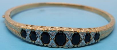 A yellow metal bangle set with seven ova