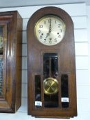An arched top oak cased wall clock with