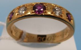 A yellow metal ring set with three rubie