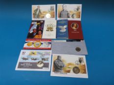 Ten commemorative coins in folders, some
