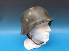 A German military helmet with camouflage finish, the leather liner marked possibly Guggenbergen